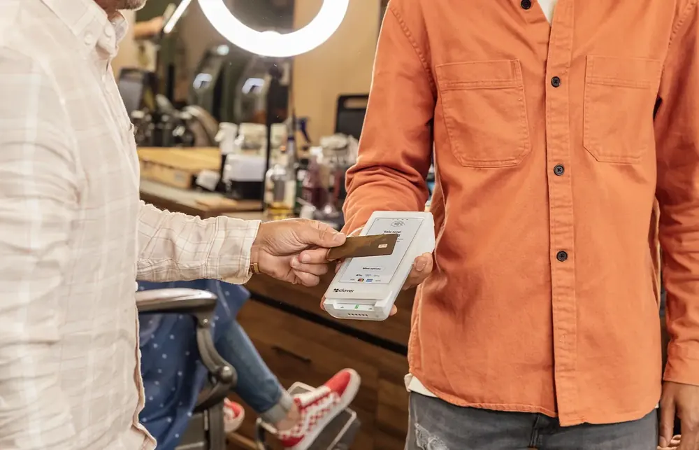 A barber taking a card payment on a Clover Flex