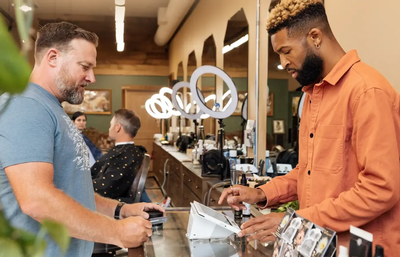 A barbershop owner ringing up a customer on a Clover Mini