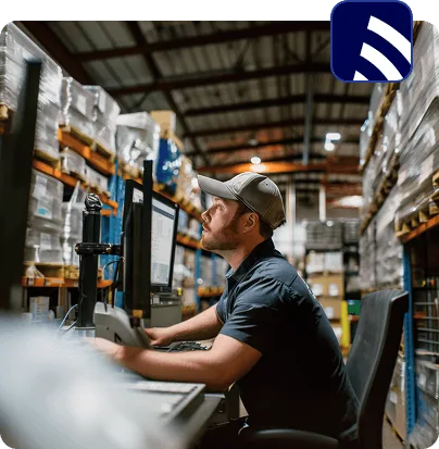 A worker checking inventory on a computer in a parts warehouse