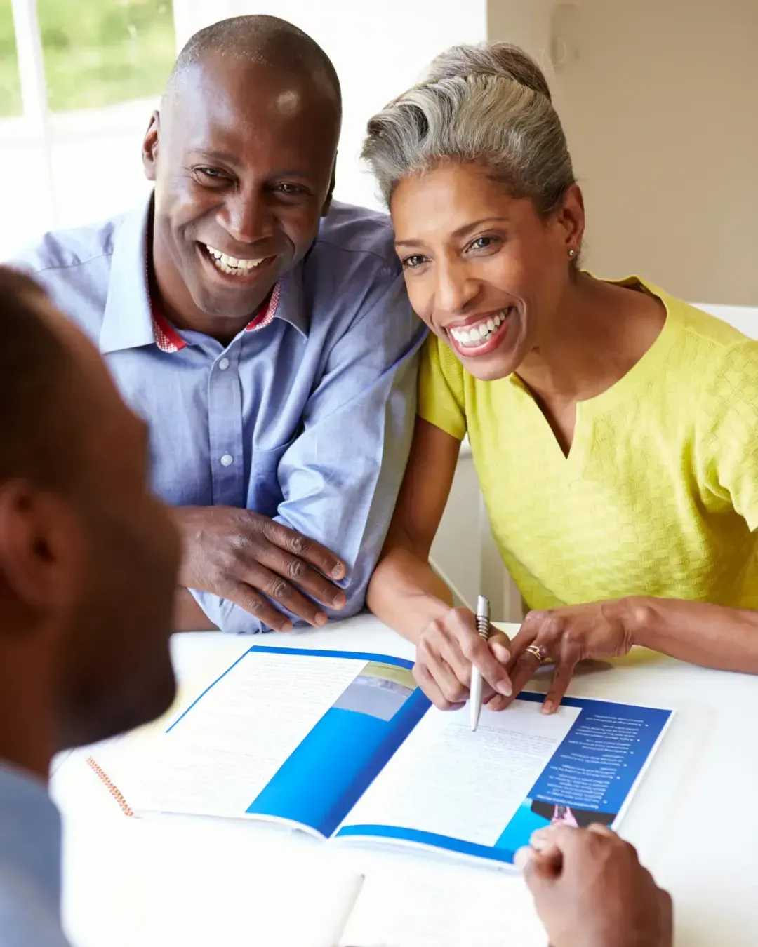 A homeowner couple reviewing financing options with a contractor at their table