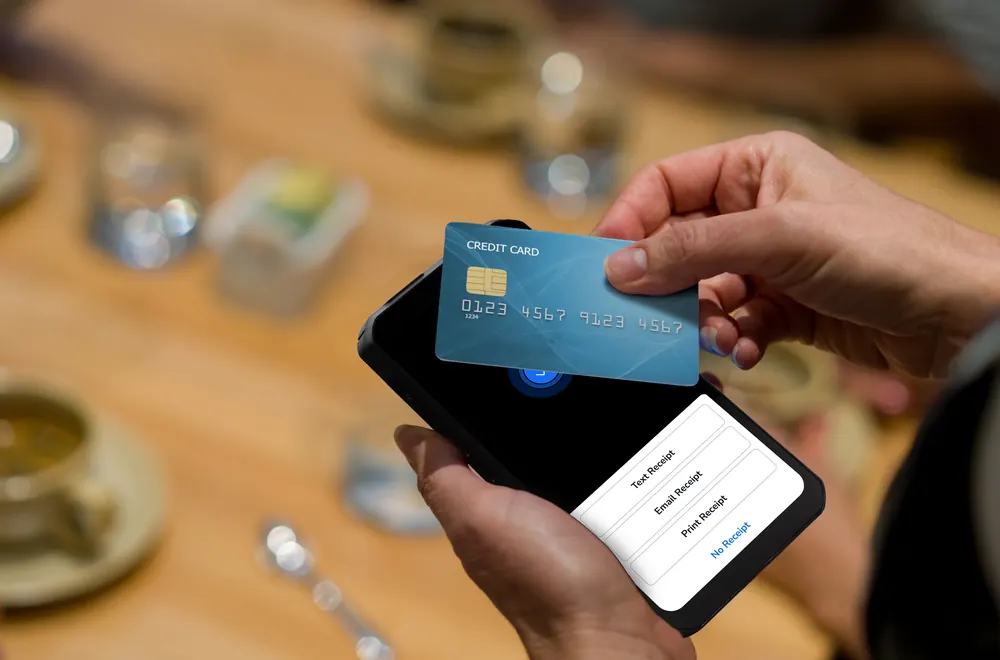 A guest tapping a card on a Shift4 Dine handheld