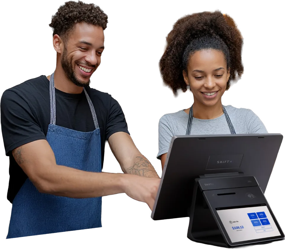 Two restaurant staff members smiling while using a Shift4 Dine POS workstation with a customer display