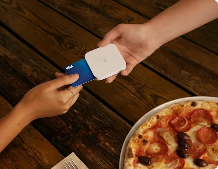 A customer paying with Square Reader at a pizza place